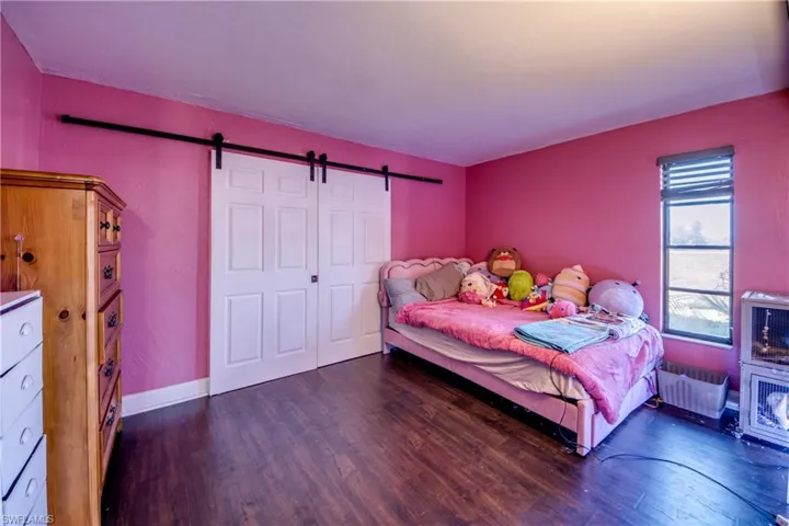 Bedroom featuring a barn door, dark wood-style floors, and radiator heating unit