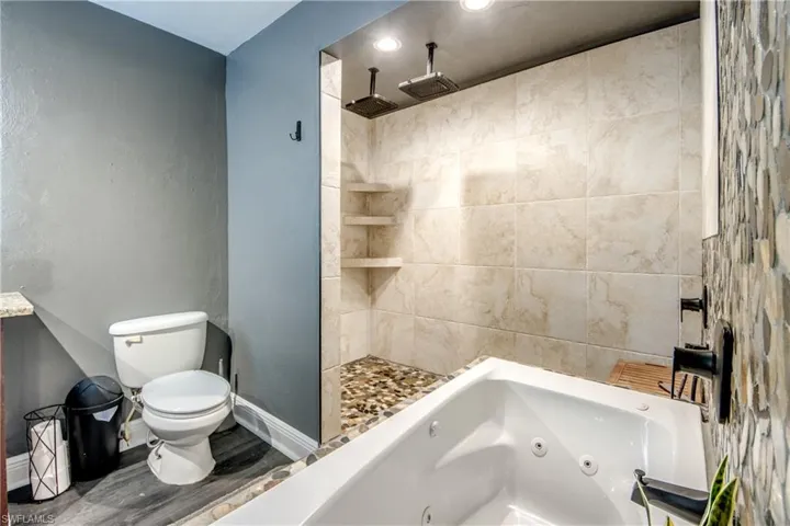 Bathroom with a tile shower, wood finished floors, recessed lighting, and a tub with jets