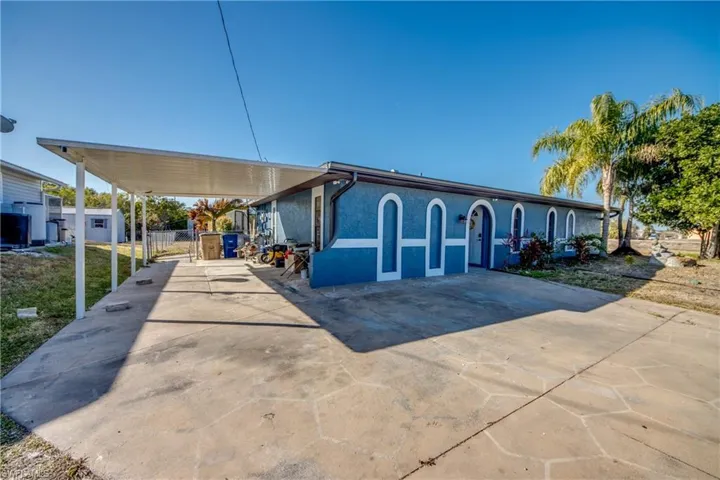 View of front of home with an attached carport, driveway, and stucco siding