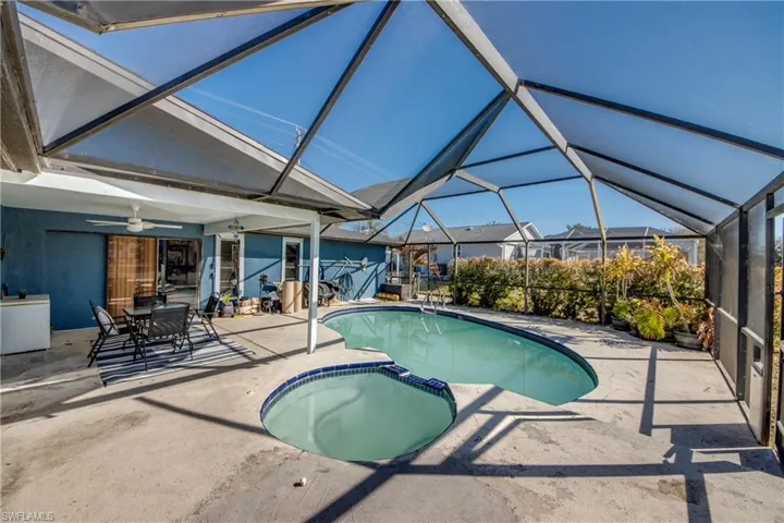 Relaxing pool / spa featuring glass enclosure, outdoor dining space, a patio area, and a sunroom