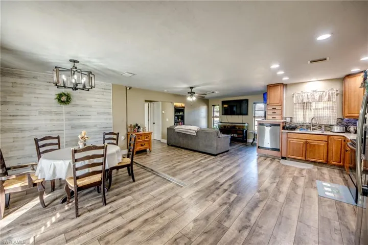 Dining room featuring wood walls, a ceiling fan, light wood finished floors, and hanging lights