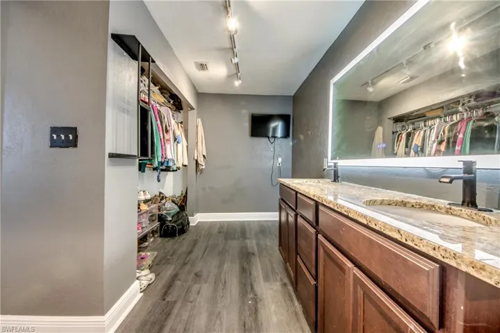Kitchen with track lighting, dark wood-style floors, and light stone countertops