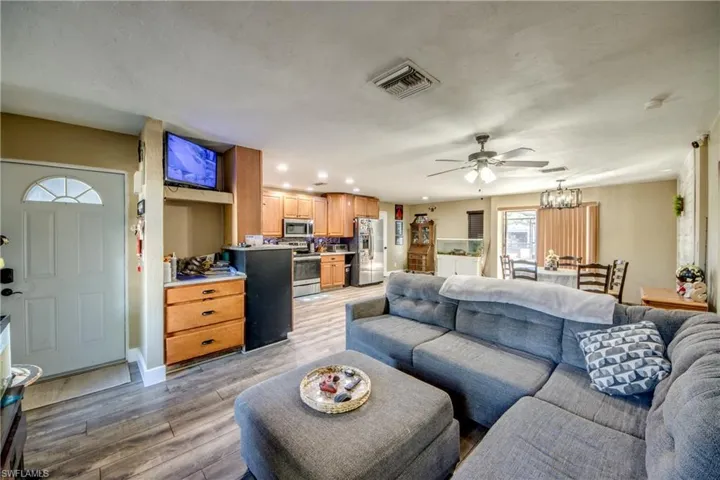 Living room featuring light wood finished floors, ceiling fan, and a chandelier