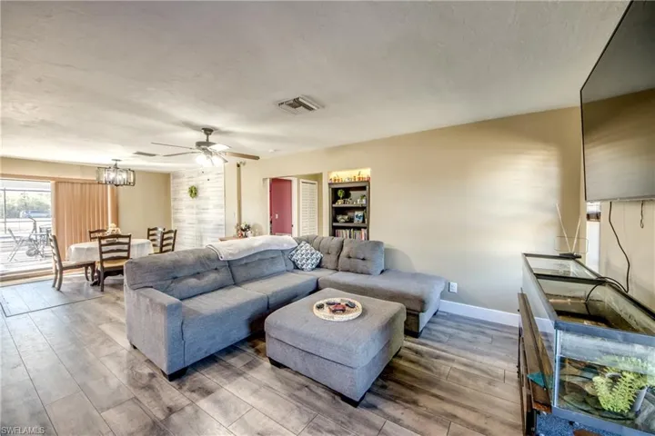 Living room with a ceiling fan, wood finished floors, a chandelier, and a textured ceiling