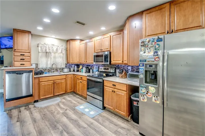 Kitchen featuring stainless steel appliances, light wood-type flooring, recessed lighting, decorative backsplash, and wood finish cabinetry