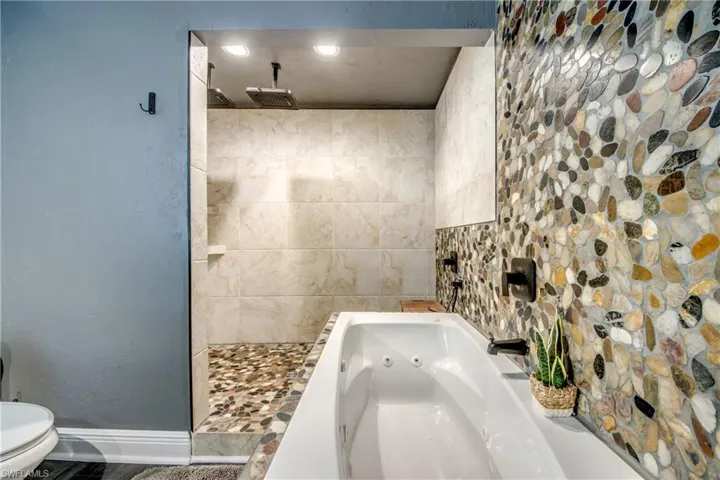 Full bathroom featuring a whirlpool tub, a textured wall, a tile shower, and recessed lighting