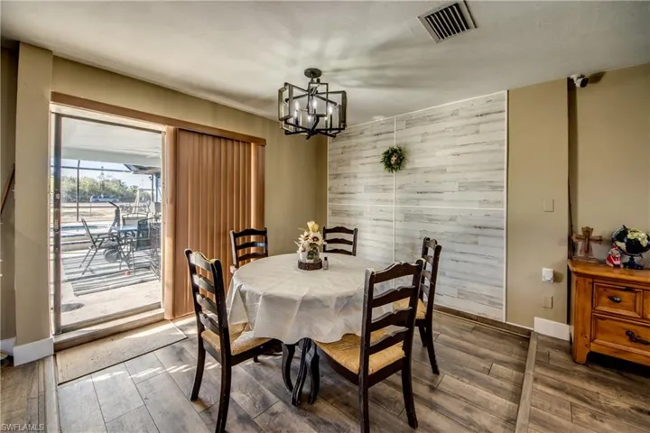 Dining room featuring wooden walls, a chandelier, wood finished floors, and an accent wall