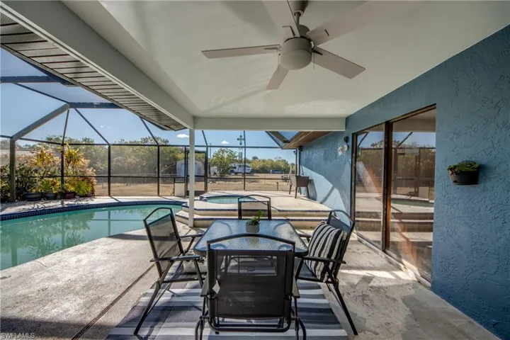 Outdoor pool featuring an in-ground hot tub, a patio, a sunroom, outdoor dining space, and a lanai