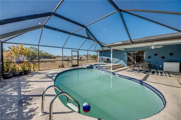 Integrated pool / spa with outdoor dining space, glass enclosure, a patio area, and a sunroom