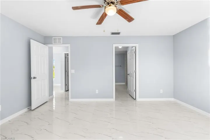 Unfurnished bedroom with a ceiling fan and light marble finish floors