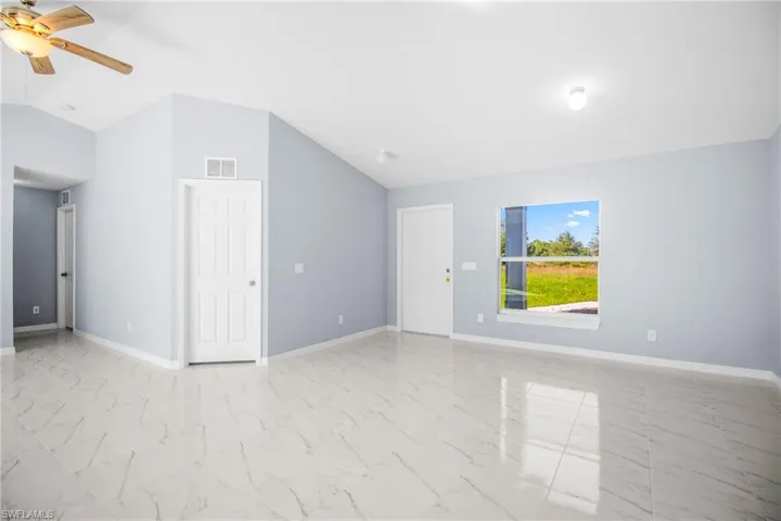 Empty room with ceiling fan and light marble finish floors