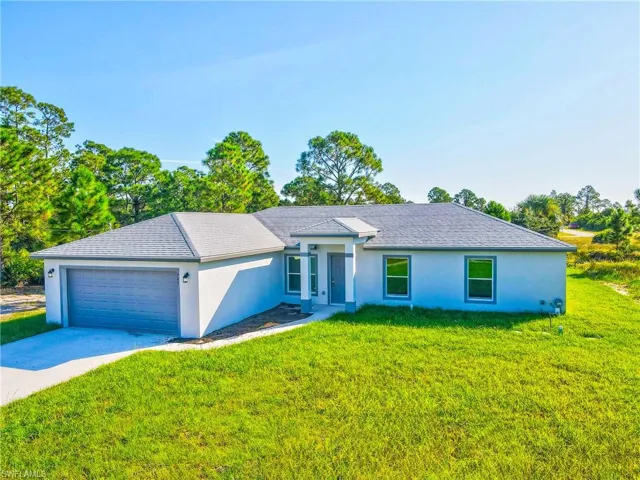 View of front of house featuring an attached garage, driveway, a front yard, and stucco siding