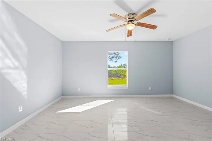 Unfurnished room featuring a ceiling fan and light marble finish floors