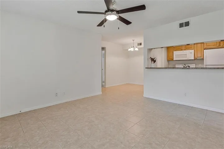 Tile floors, ceiling fan view into kitchen