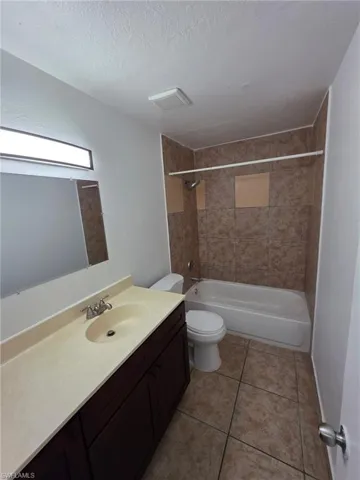 Bathroom with vanity,  shower combination, light tile patterned flooring, and a textured ceiling