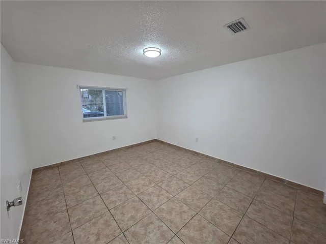 Empty room with a textured ceiling and light tile patterned flooring