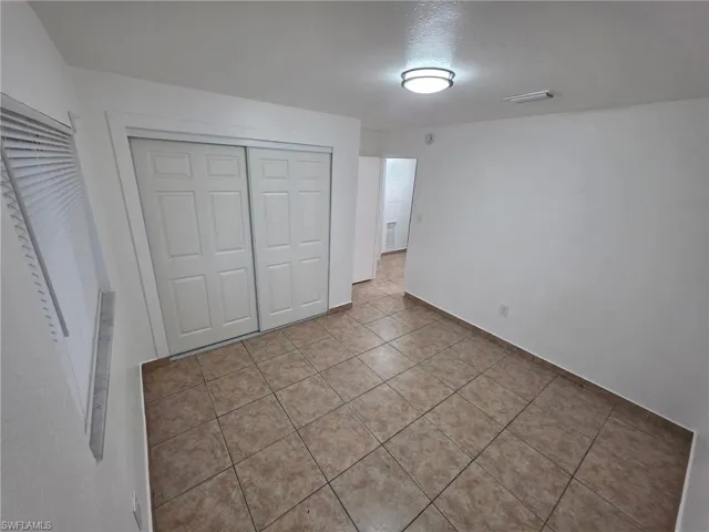 Unfurnished bedroom with a closet, a textured ceiling, and tile patterned floors