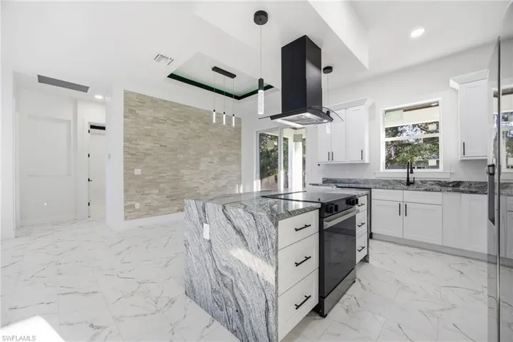 Kitchen with electric range, dark stone countertops, pendant lighting, a kitchen island, and island exhaust hood