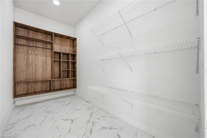 Walk in closet featuring light marble finish floors