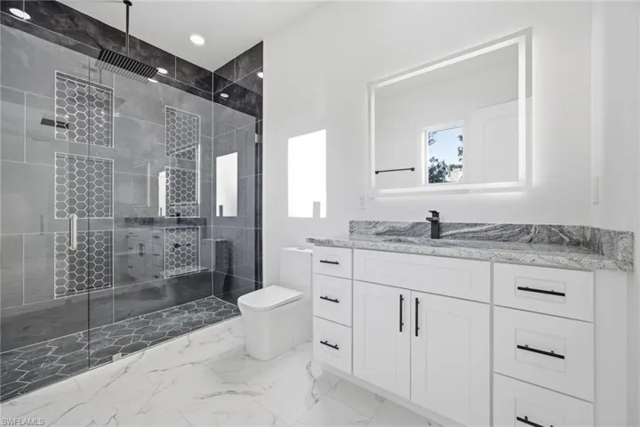 Full bathroom featuring vanity, light marble finish floors, a stall shower, and recessed lighting