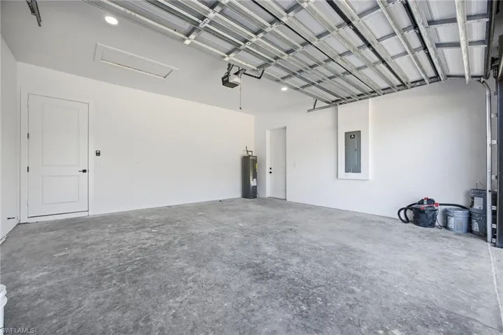 Garage featuring electric panel and electric water heater