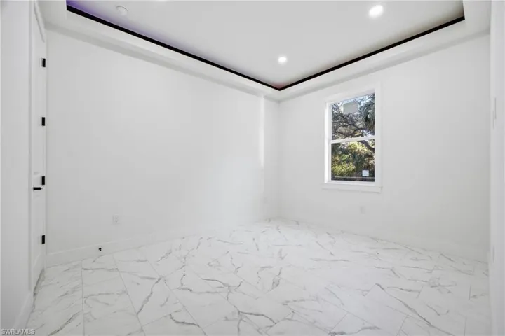 Empty room with light marble finish floors and recessed lighting