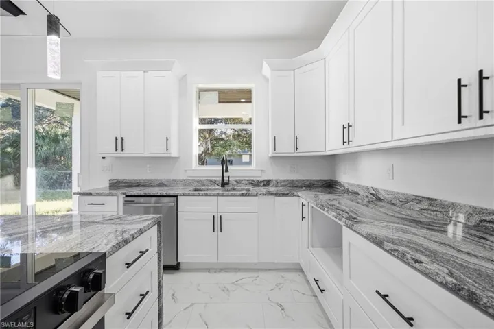 Kitchen featuring black / electric stove, white cabinets, stainless steel dishwasher, hanging light fixtures, and light marble finish flooring