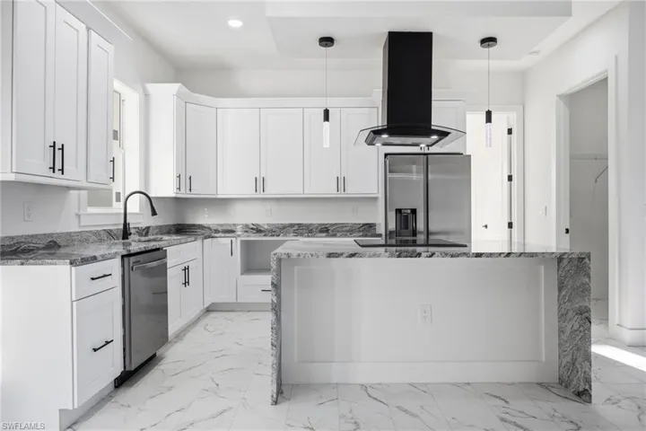 Kitchen featuring dark stone counters, light marble finish flooring, a kitchen island, extractor fan, and recessed lighting