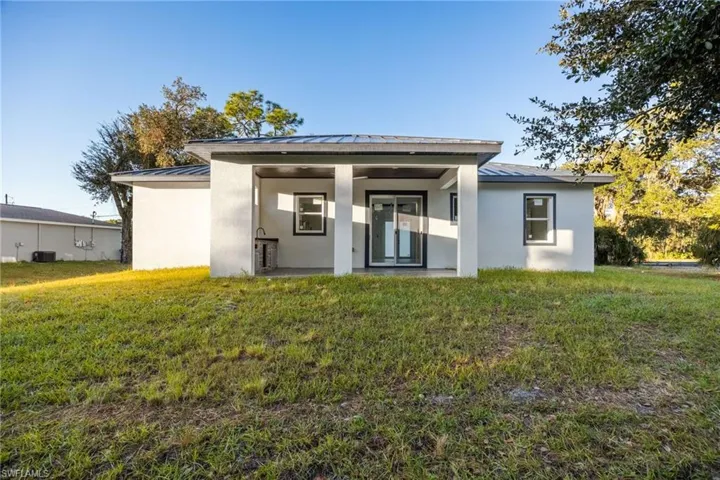 Rear view of property featuring a standing seam roof, a metal roof, and a yard