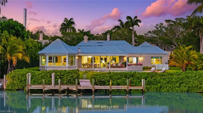 Back of house with a chimney, a water view, and a patio