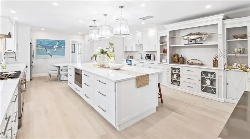 Kitchen featuring white cabinetry, hanging light fixtures, stainless steel appliances, and light wood-style floors