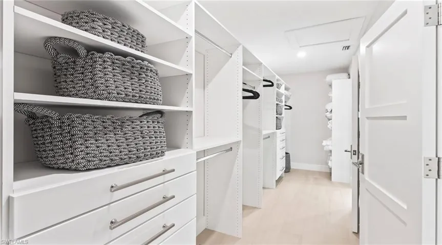 Walk in closet with attic access and light wood-style floors