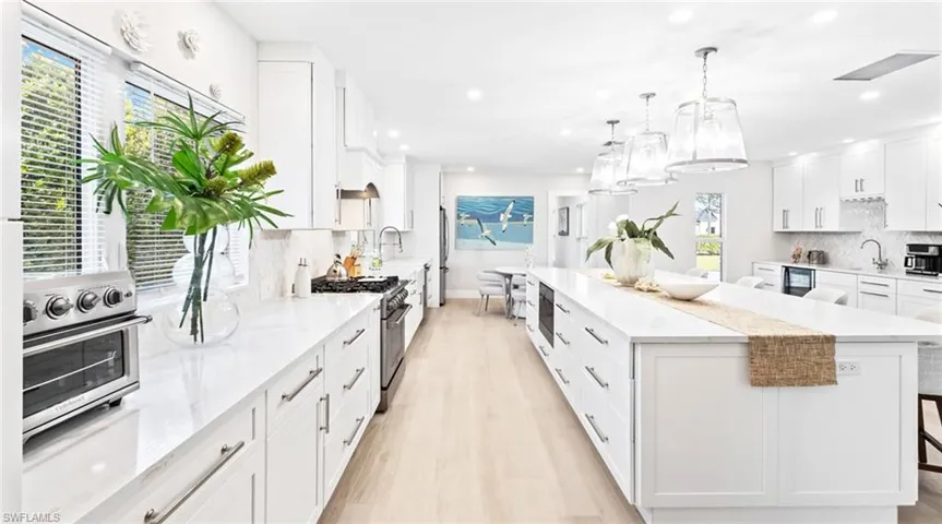 Kitchen with white cabinetry, backsplash, a breakfast bar area, and hanging light fixtures