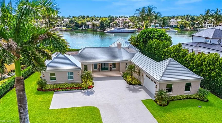 View of front of property featuring a water view, driveway, a garage, a front lawn, and a residential view