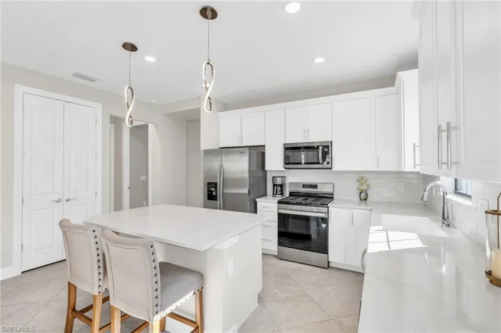 Kitchen with pendant lighting, a center island, white cabinets, and appliances with stainless steel finishes