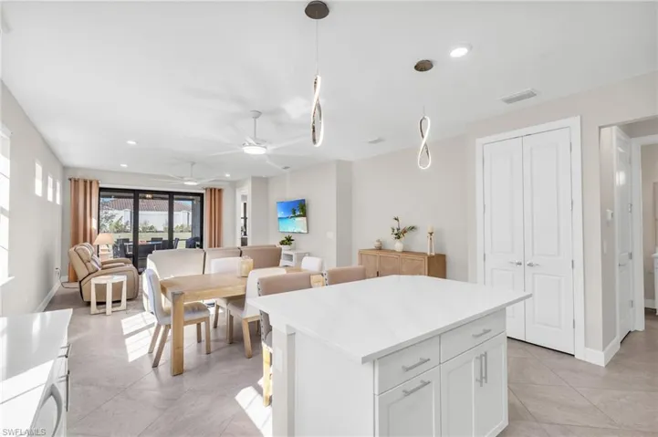 Kitchen featuring ceiling fan, hanging light fixtures, a center island, white cabinets, and light tile patterned flooring