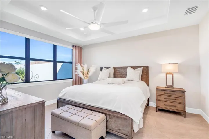 Bedroom featuring a raised ceiling, ceiling fan, and light tile patterned flooring