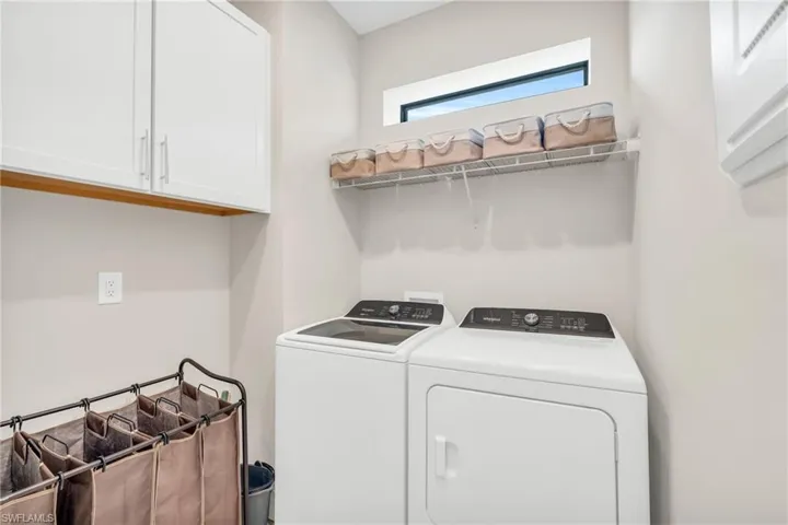 Clothes washing area featuring cabinets and washer and clothes dryer