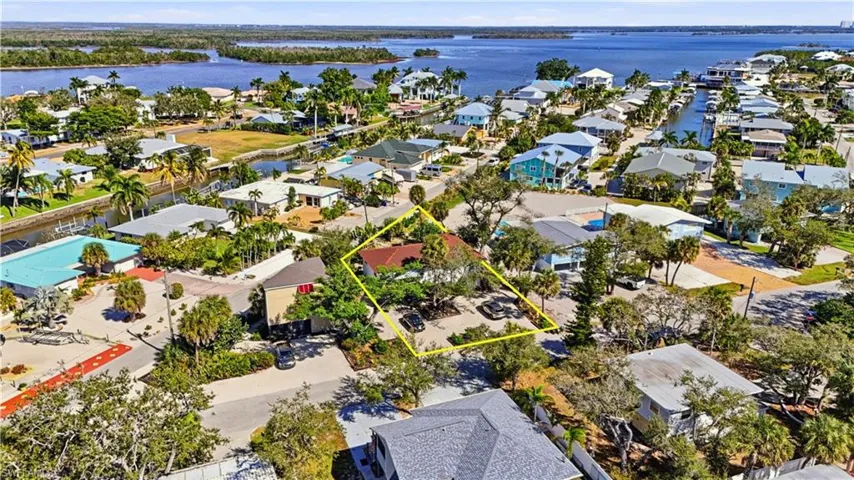 Aerial perspective of suburban area featuring a nearby body of water and property boundaries highlighted - Virtually Edited Image