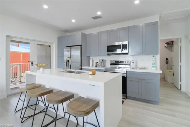 Kitchen with a kitchen island with sink, appliances with stainless steel finishes, a breakfast bar area, light wood-type flooring, and sink