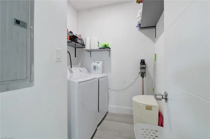 Laundry area featuring washer and dryer, electric panel, and light hardwood / wood-style floors