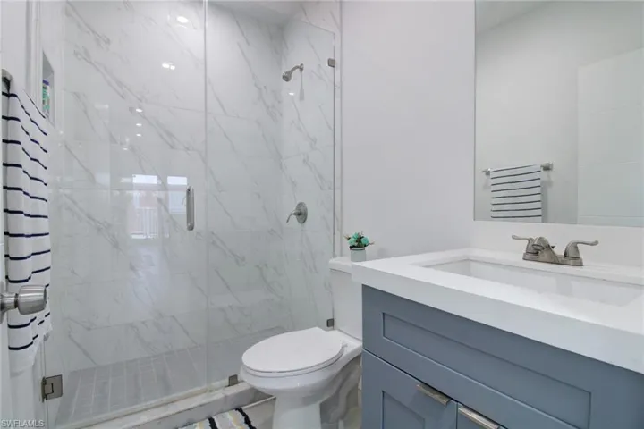 Bathroom featuring an enclosed shower, vanity, and toilet