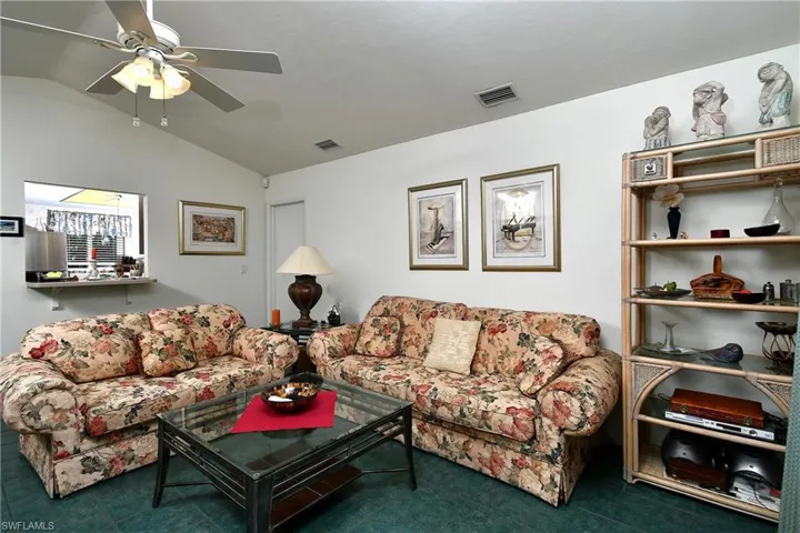 Carpeted living room with lofted ceiling and ceiling fan