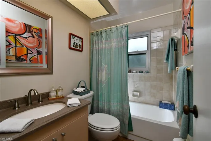 Full bathroom with vanity, shower / bath combination with curtain, and toilet