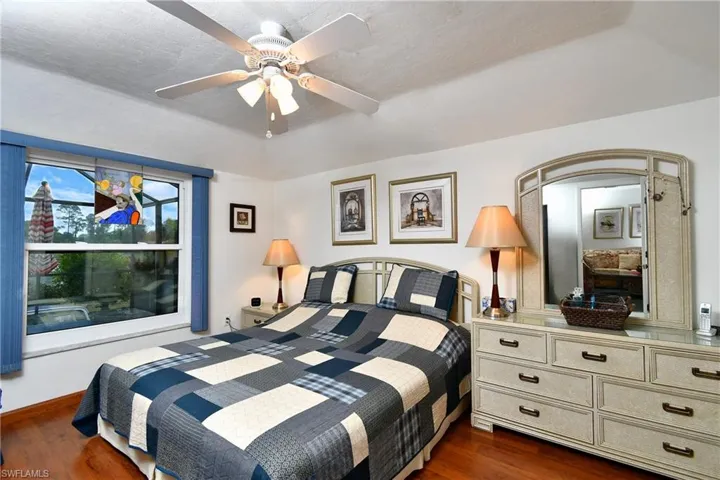Bedroom featuring ceiling fan, dark hardwood / wood-style floors, and a textured ceiling