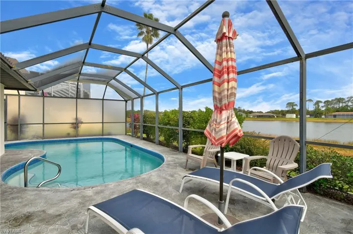 View of swimming pool featuring a patio, a water view, and glass enclosure