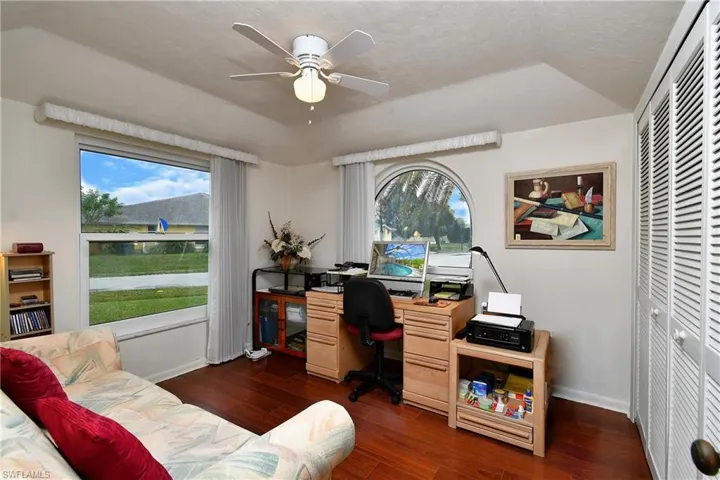 Office area with dark hardwood / wood-style flooring and ceiling fan