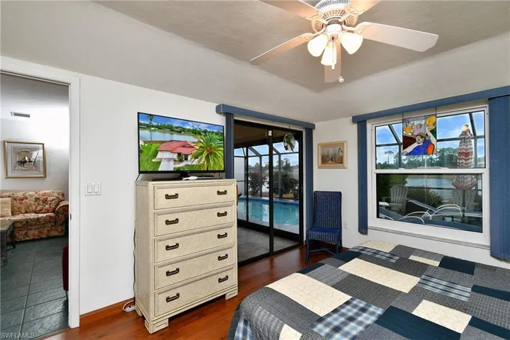 Bedroom with dark wood-type flooring, access to exterior, and ceiling fan