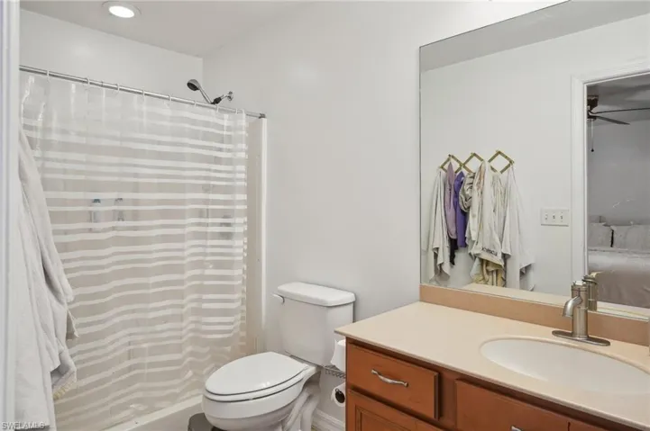 Bathroom with vanity, toilet, ceiling fan, and curtained shower