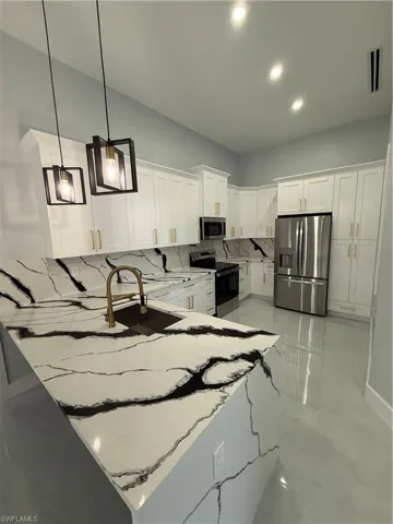 Kitchen with white cabinetry, fridge, a peninsula, stainless steel electric stove, and pendant lighting